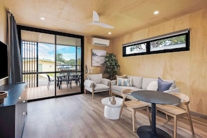 Un soggiorno moderno con divano, tavolino, poltrone, televisore e un balcone con vista.