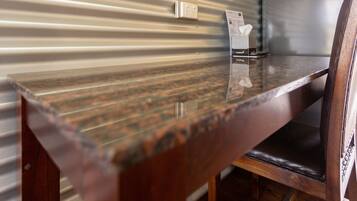 A wooden table with a reflective surface, a chair with a cushioned seat, and a wall with a corrugated metal design.