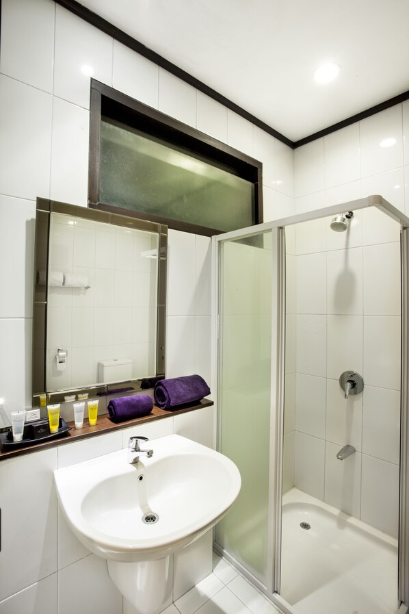 A bathroom with a white sink, a glass-enclosed shower, and a mirror above the sink.
