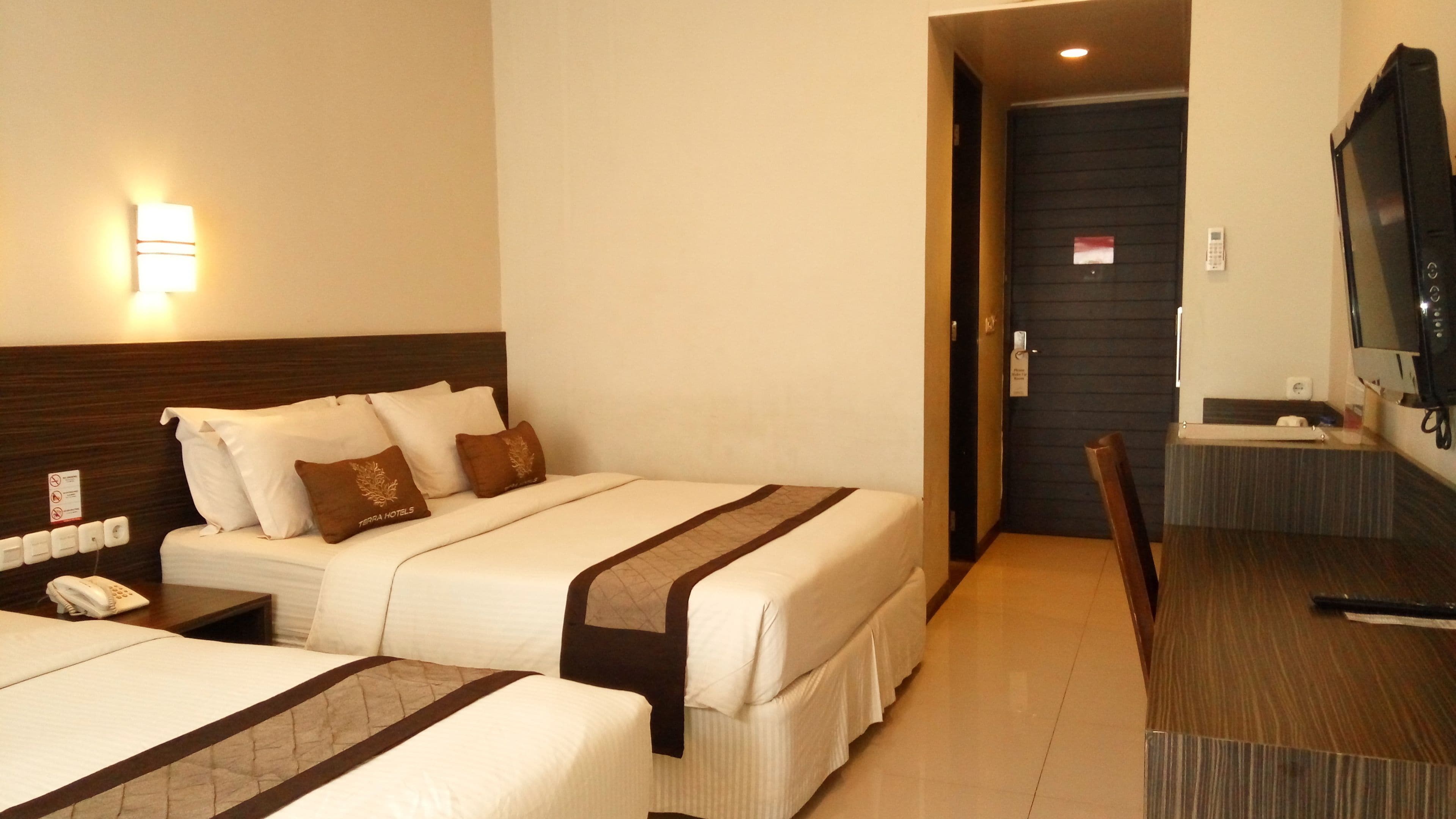 A hotel room with two beds, a TV, a desk, and a bathroom door.