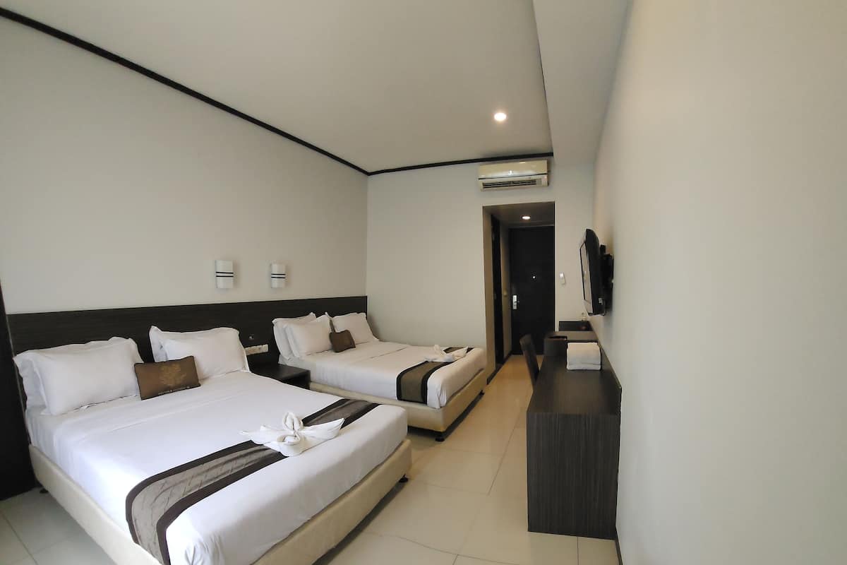 A hotel room with two beds, a desk, a chair, and a TV.