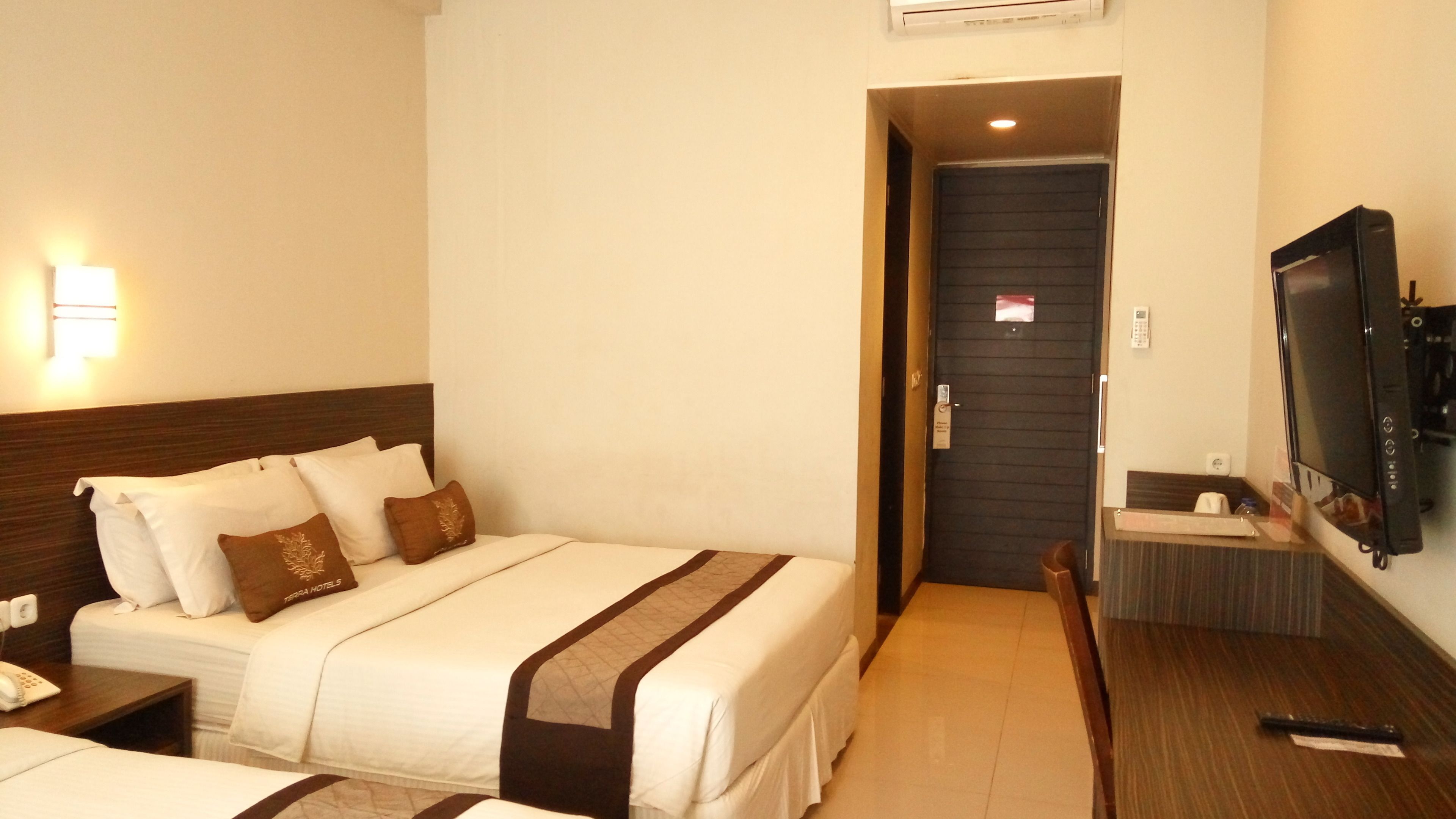 A hotel room with a bed, bedside table, and a TV.