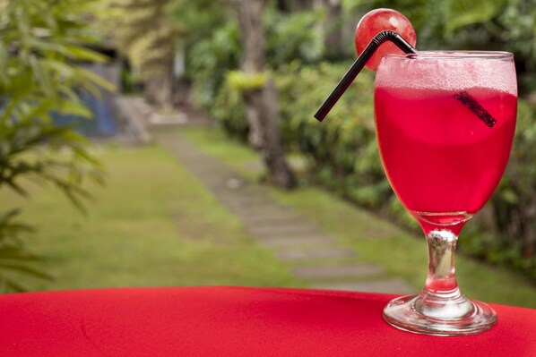 A cocktail in a glass with a straw and a cherry on a red tablecloth. - Summer Hills Hotel (Bandung)