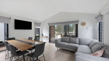 Una sala moderna con una mesa de comedor de madera, un sofá gris y sillas negras.
