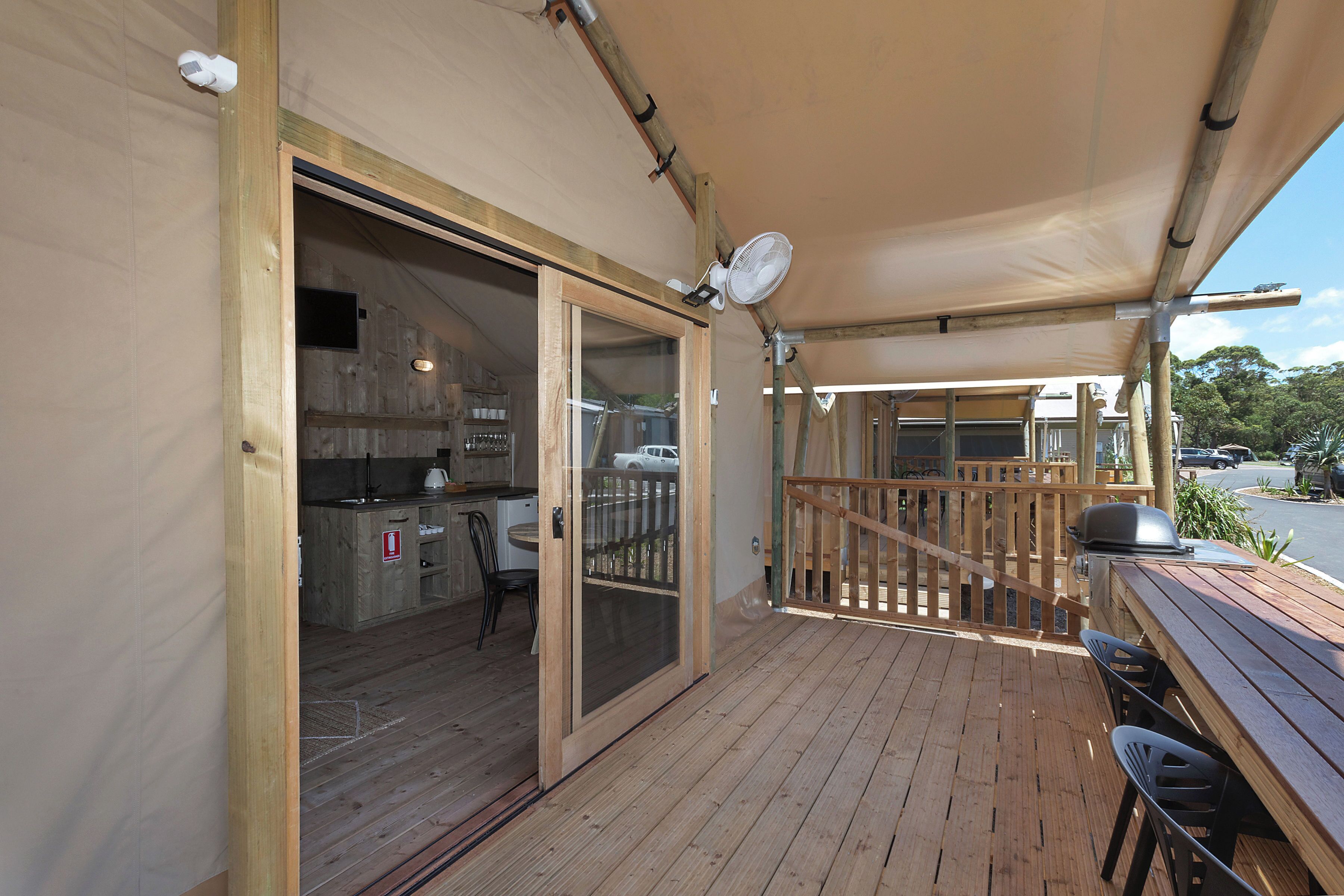 Una terraza de madera con una parrilla, una mesa y sillas.