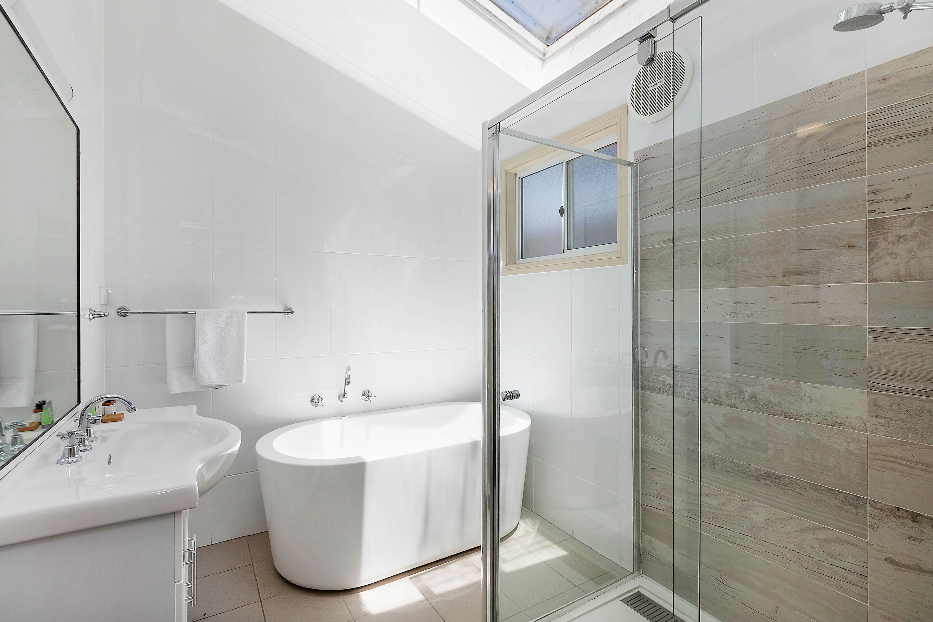A modern bathroom with a glass-enclosed shower, a freestanding bathtub, and a sink.