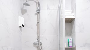 Un baño moderno con ducha, inodoro y azulejos de mármol.