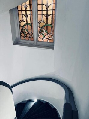 A spiral staircase with a small window above it. - Hotel Abberdeen (Brussels)