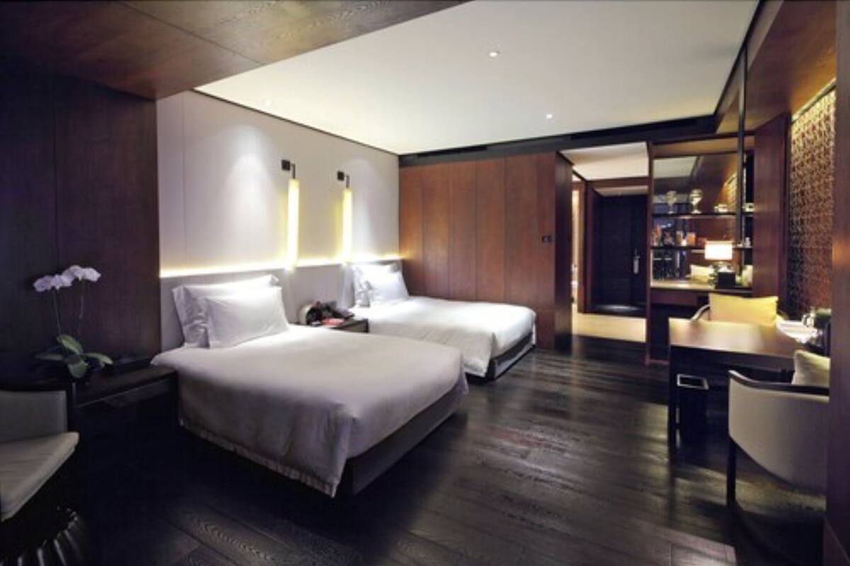 A modern hotel room with two beds, a desk, and a bathroom.