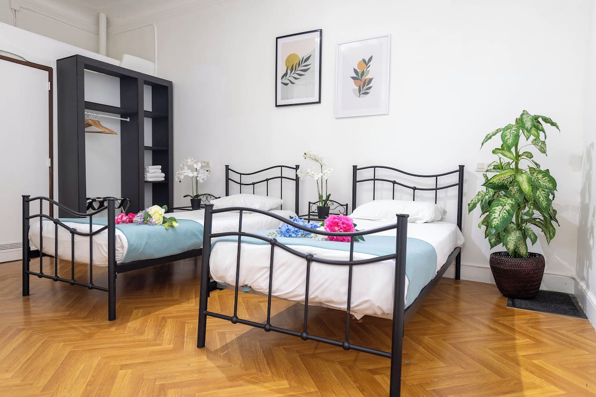 A room with two beds, a wardrobe, and a potted plant.