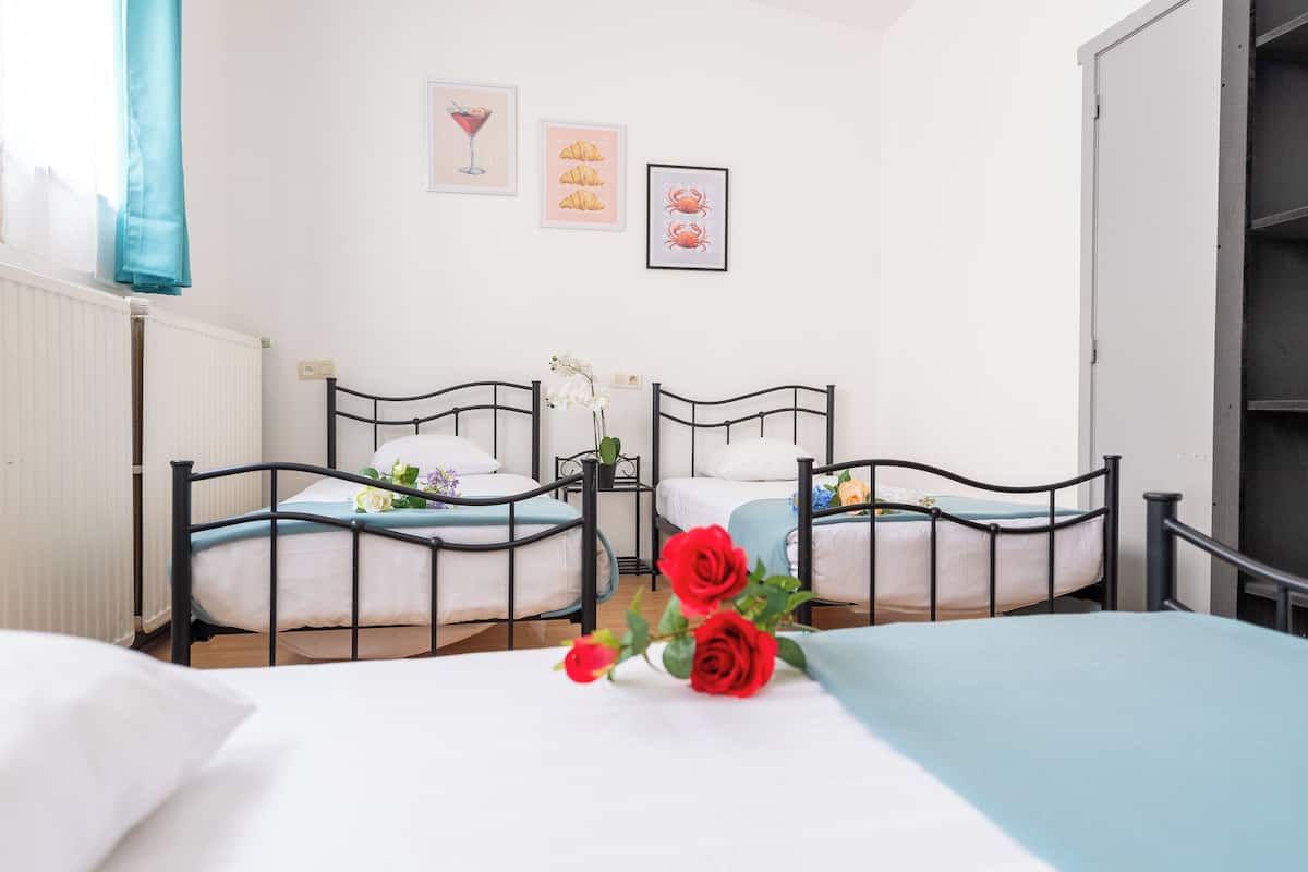 A hotel room with two single beds, a large bed, and a view of the city.