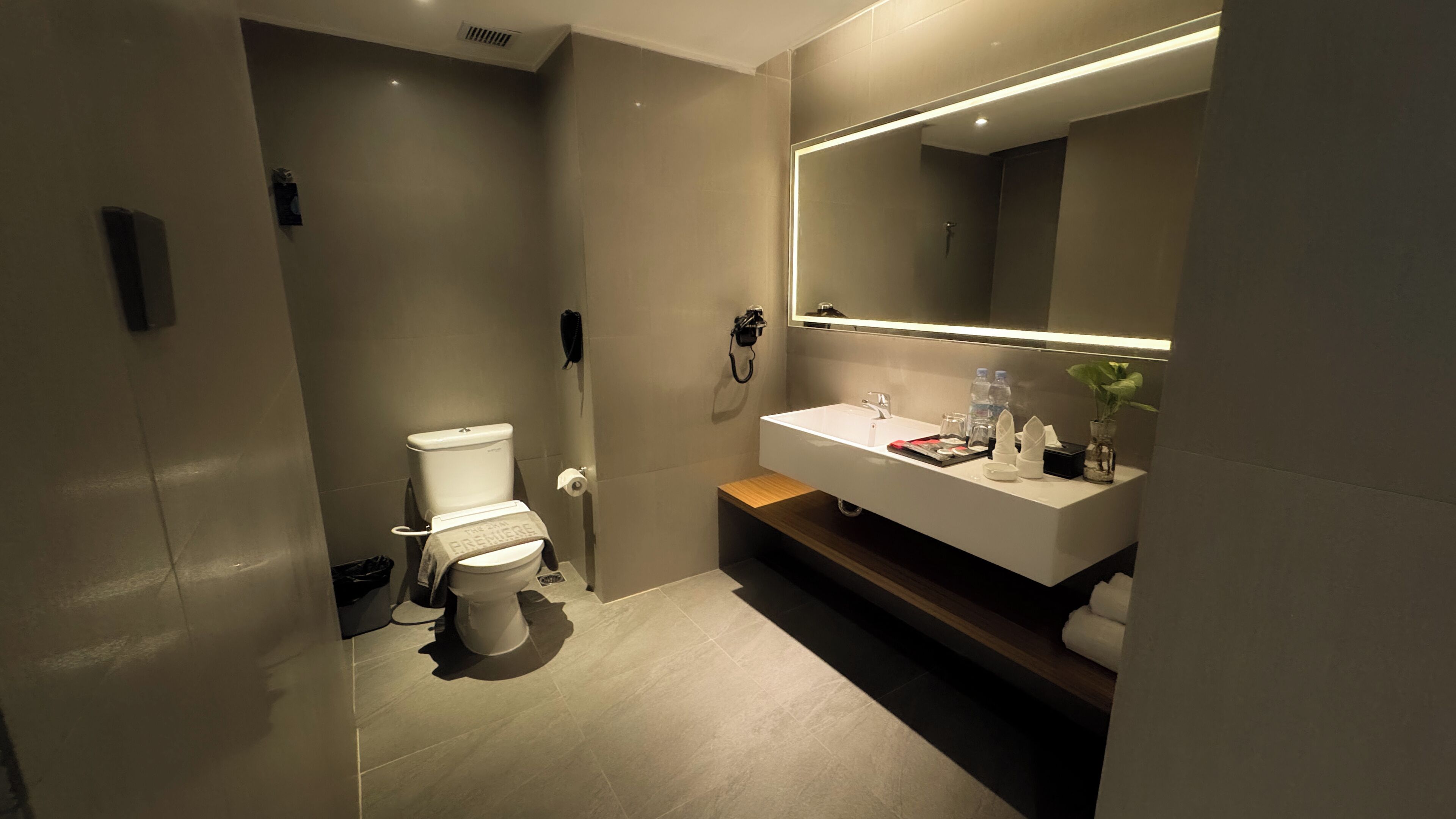 Un baño moderno con inodoro, lavamanos y espejo grande.