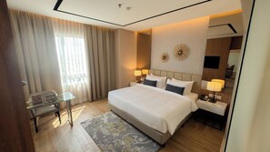 Une chambre d’hôtel avec un grand lit, des lampes de chevet, une petite table et un miroir.