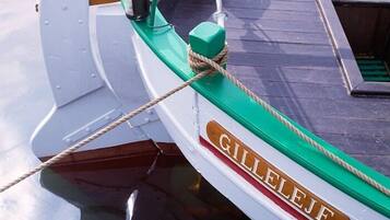 A boat named GILLEJE with a green and white color scheme, a rope tied to a cleat, and a metal cleat on the side.