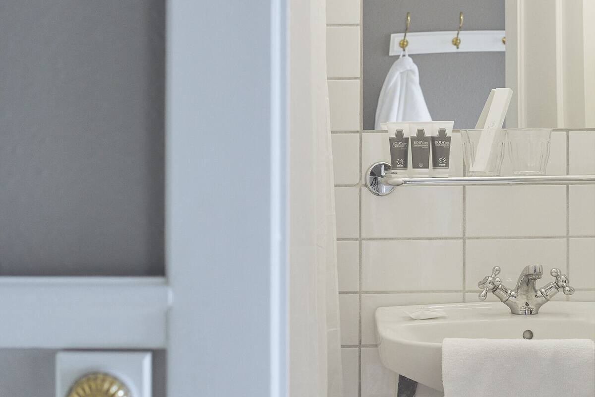 A bathroom with a sink, mirror, and towel rack.