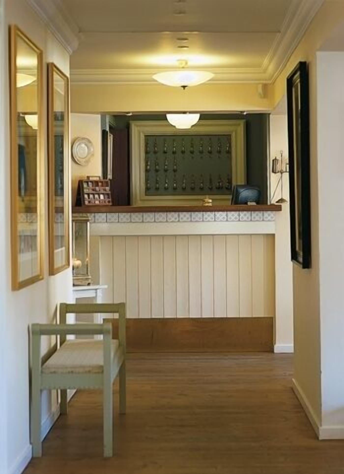 A hallway with a wooden bench, a wall-mounted light fixture, and a framed mirror.