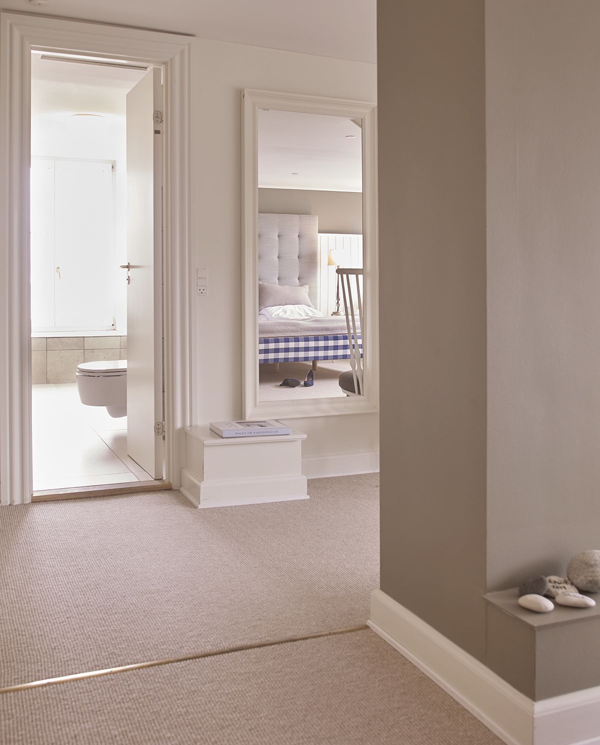 Un dormitorio con cama, ventana, mesita de noche y vistas al baño.