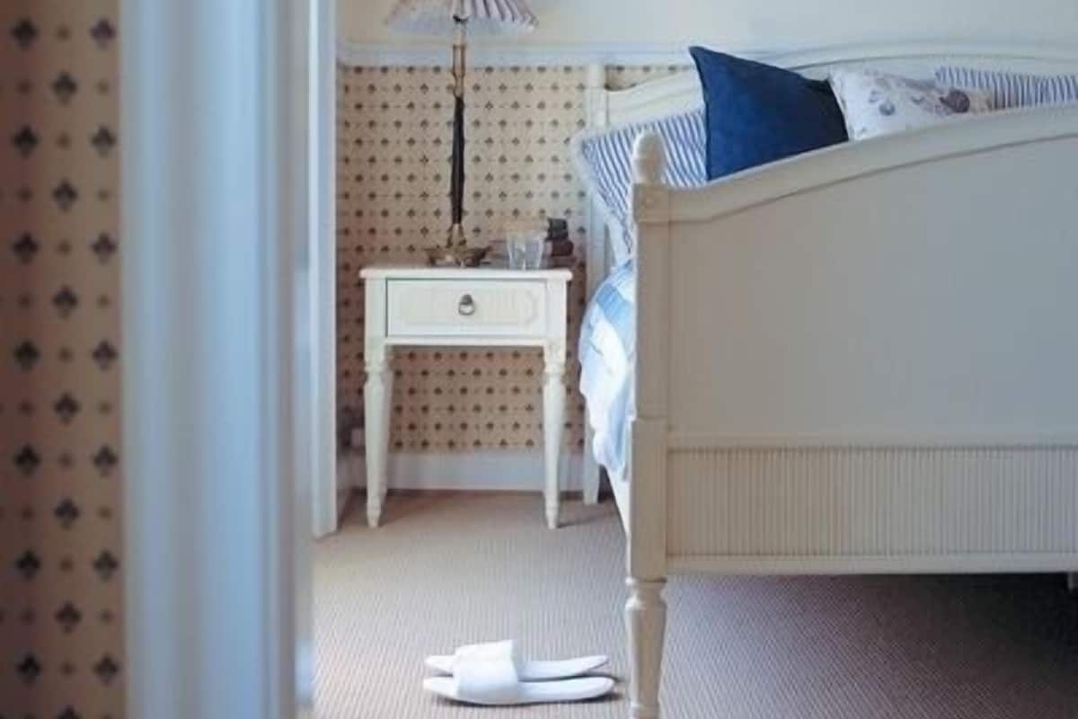 A bedroom with a bed, a nightstand, a lamp, and a patterned wall.