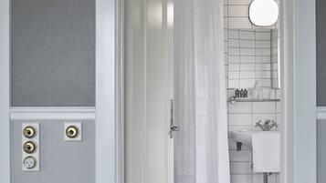 Un baño con inodoro blanco, lavamanos, espejo y cortina de ducha.