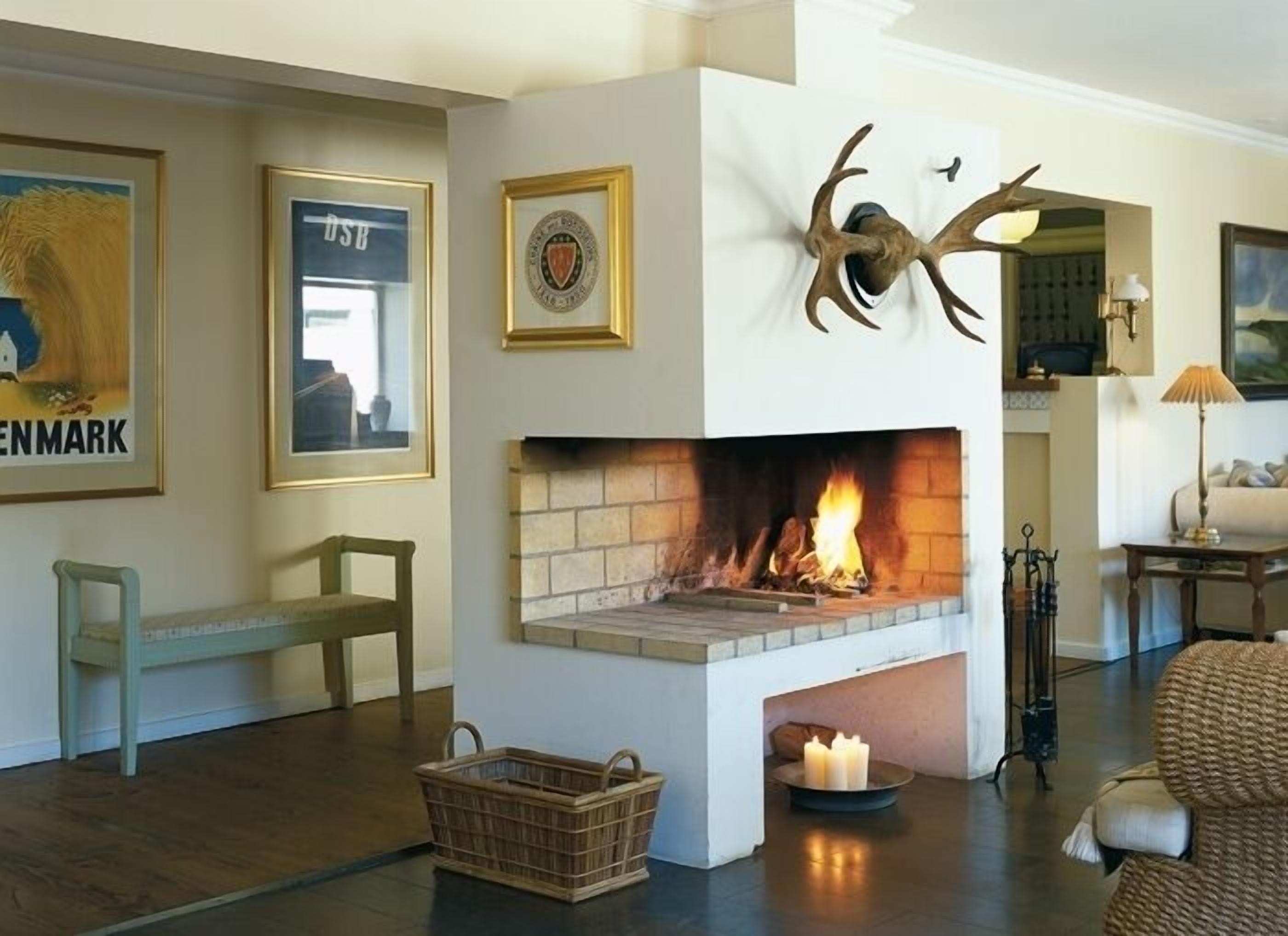 A living room with a fireplace, framed pictures, a wicker basket, and a sofa.
