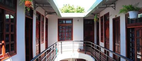 A covered courtyard with a central open space, surrounded by buildings with wooden doors and windows.