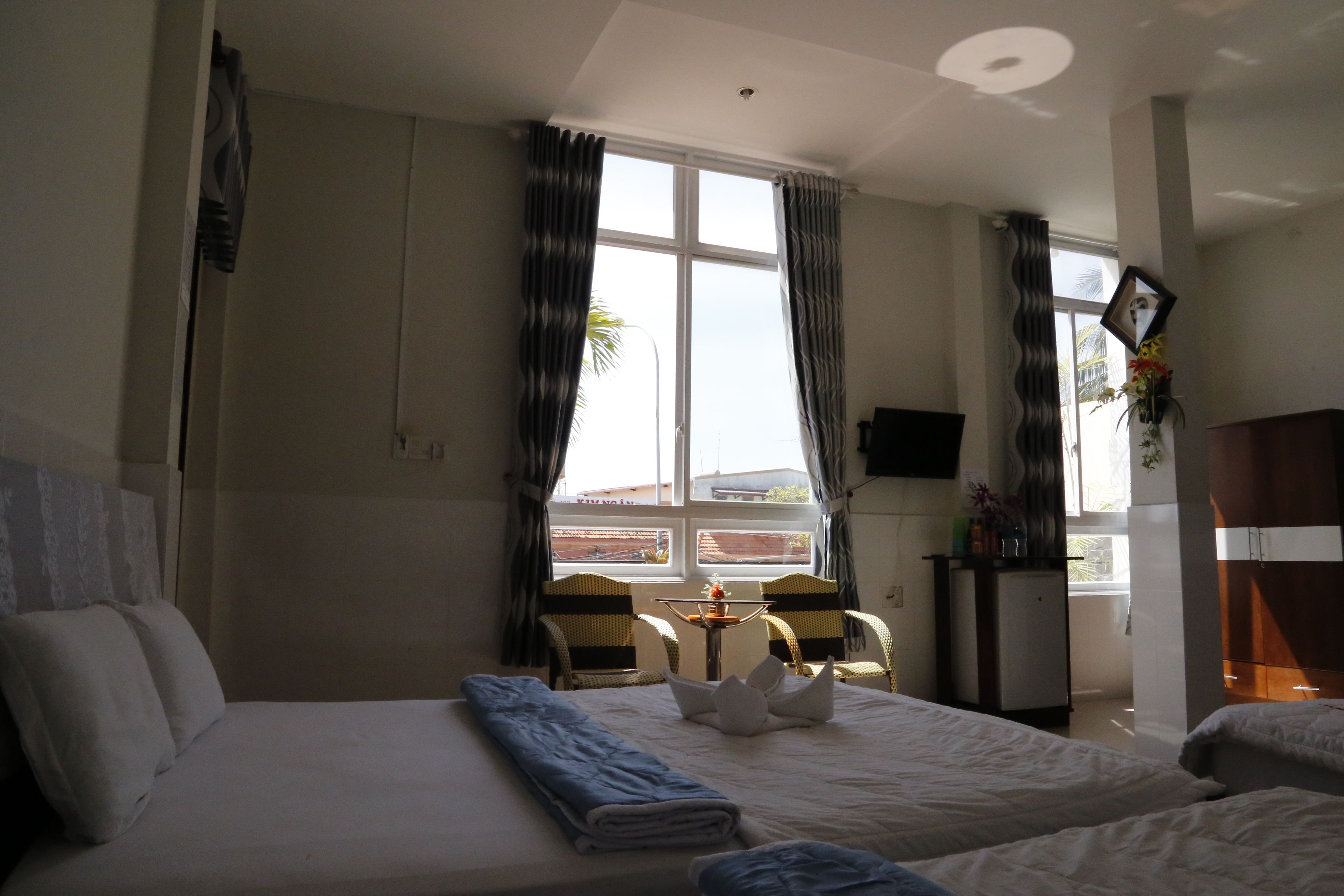 A hotel room with a bed, two chairs, a small table, and a TV.