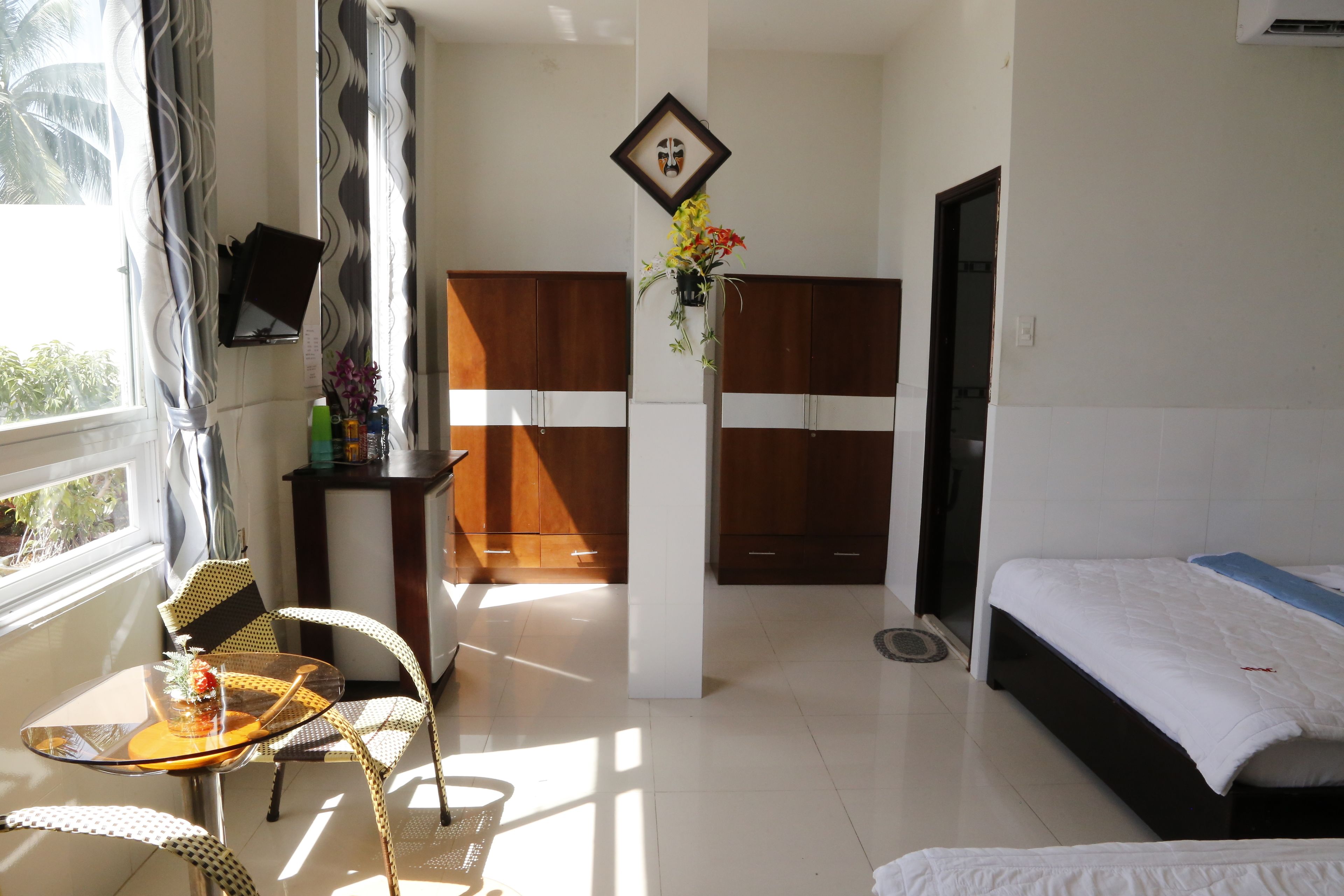 A hotel room with a bed, a small table with chairs, a TV, and a window with curtains.
