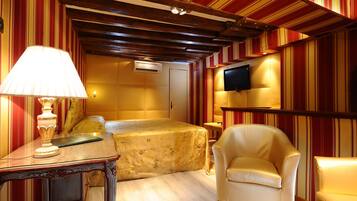 Classic hotel room with a double bed, wooden nightstand, and leather armchair.