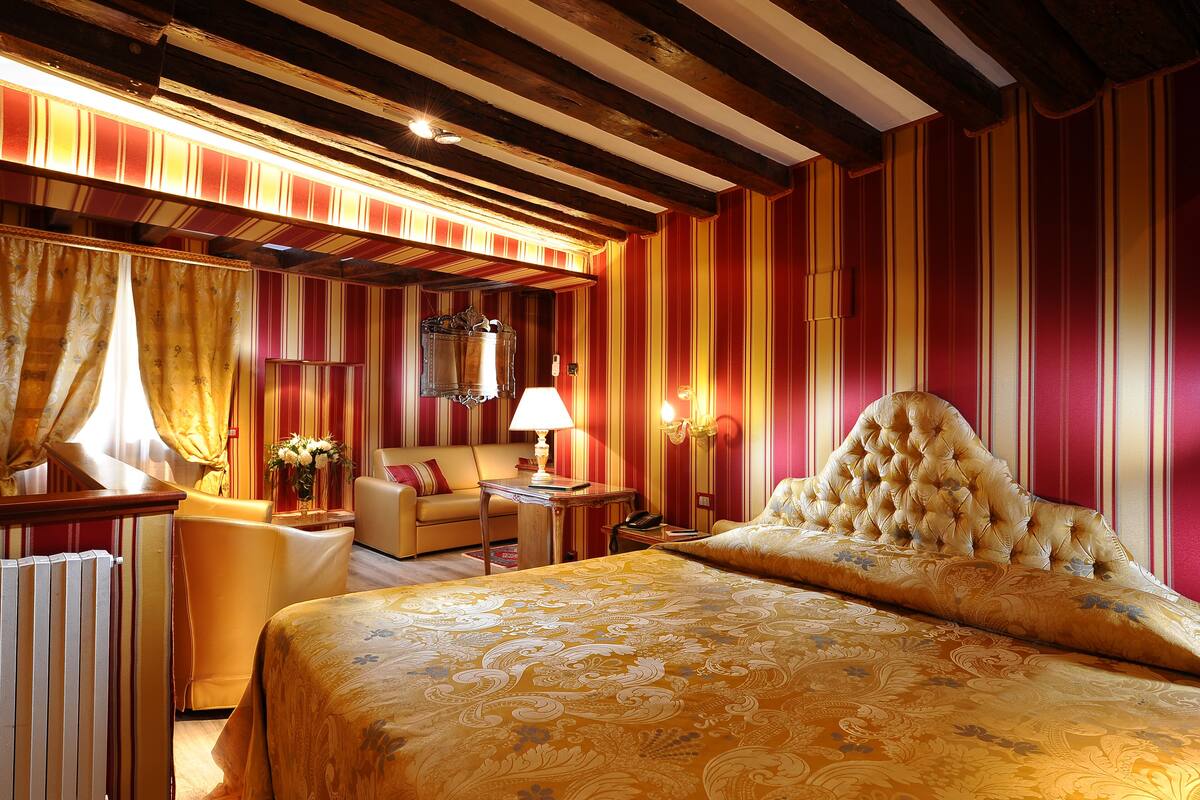 A hotel room with a large bed, a sofa, a table, and a chair.