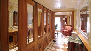 A hallway with wooden paneling, a checkered floor, and a seating area with a red chair. - Hotel Ca Marinella (Venice)