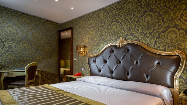 A hotel room with a large bed, a desk, and a chair. - Hotel Ca Marinella (Venice)