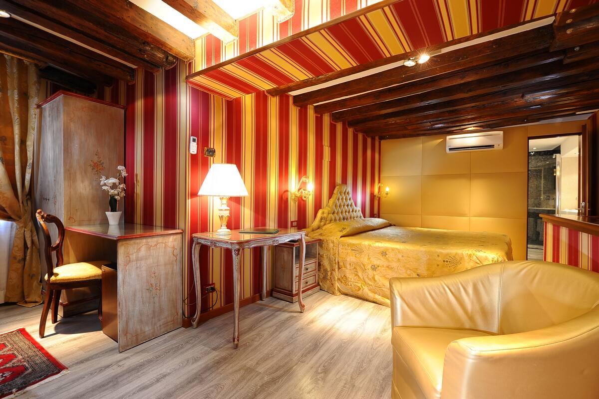 A room with a bed, a desk, a chair, and a lamp.