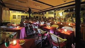 An indoor dining area with tables and chairs, candles, and a view of buildings outside. - Hotel Ca Marinella (Venice)