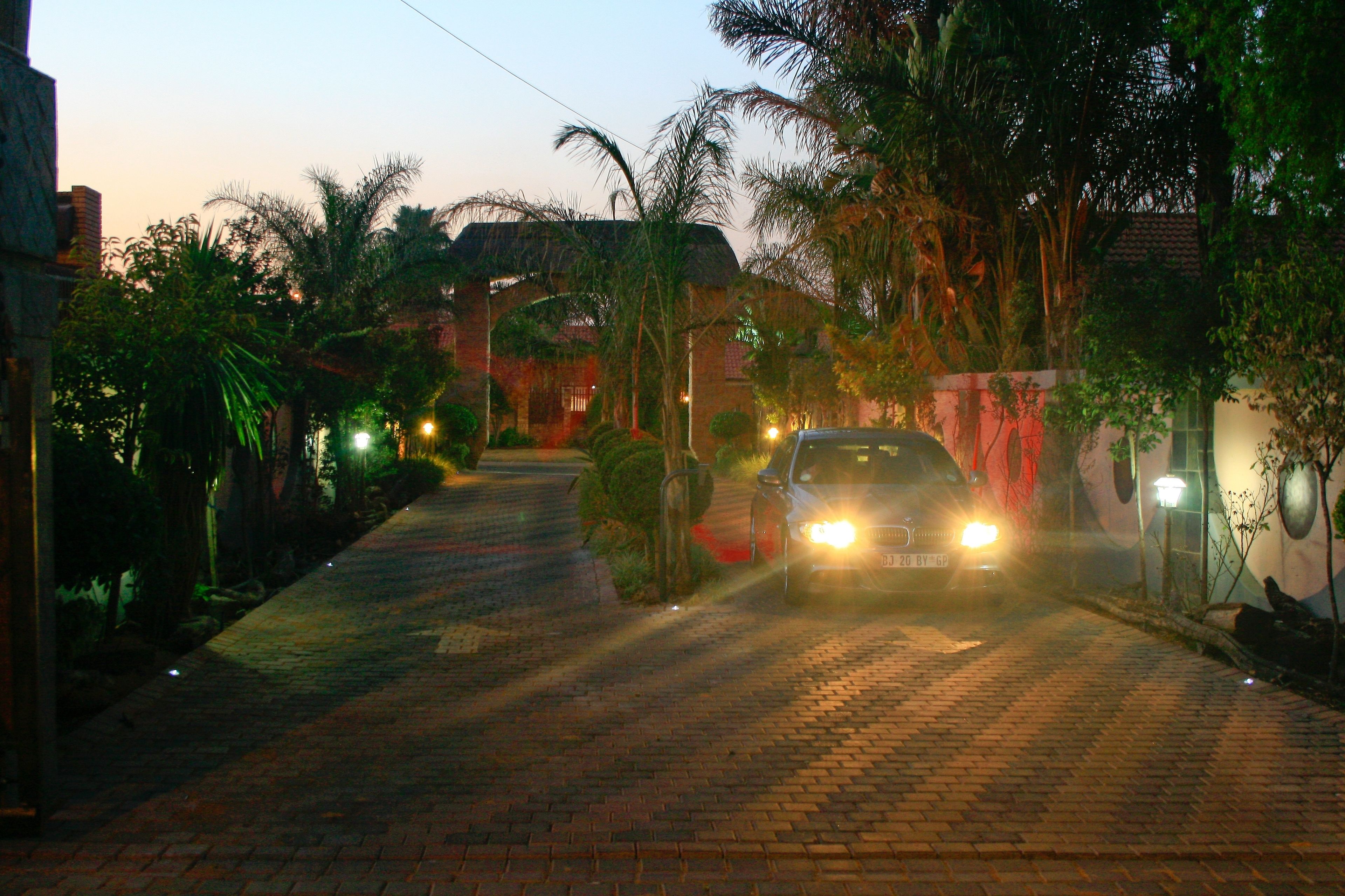 A car driving down a brick-paved road at dusk.