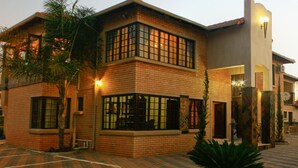 Un edificio de dos pisos con fachada de ladrillo, ventanas amplias y un patio empedrado.