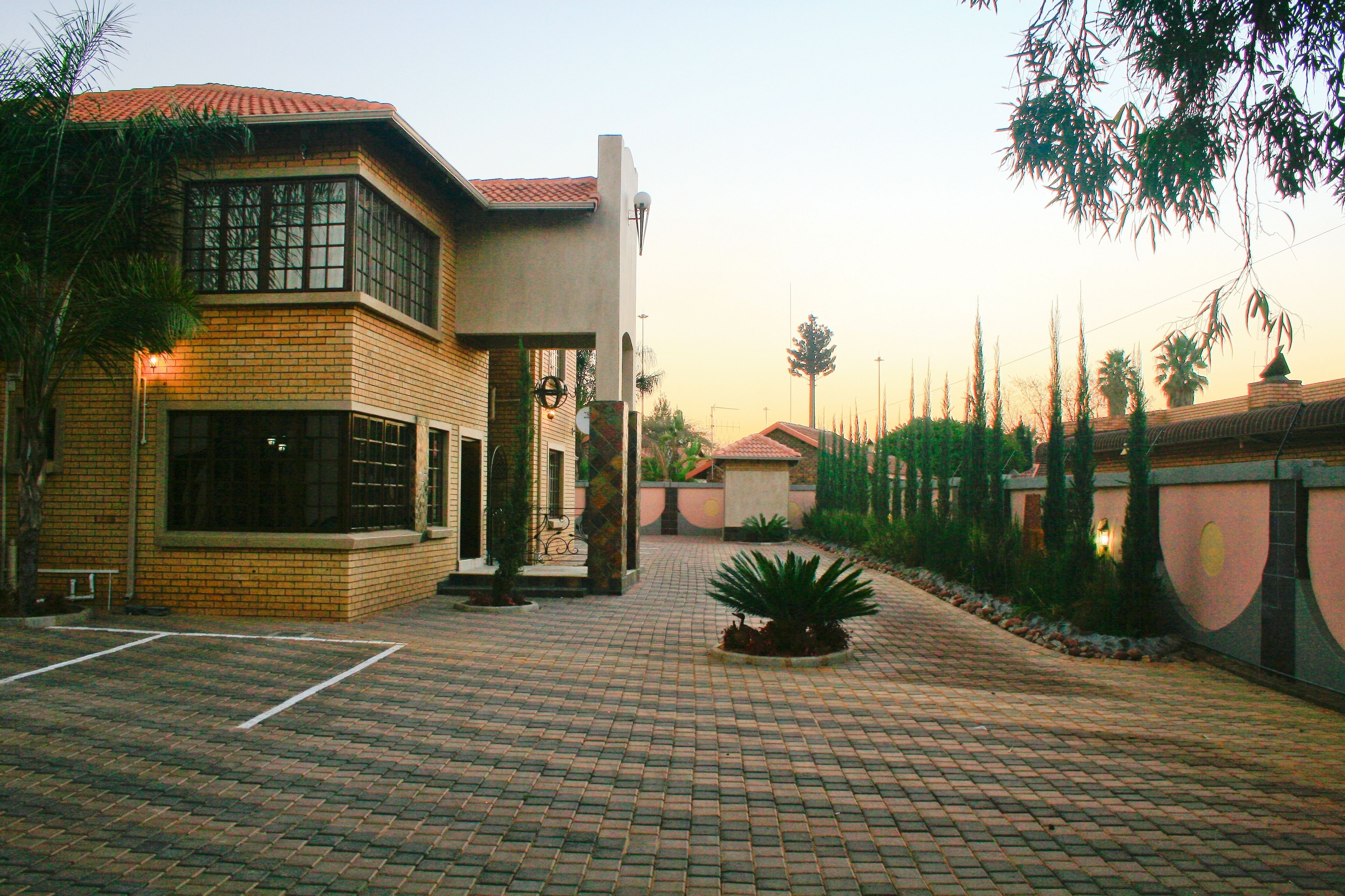 Un patio con un sendero empedrado, un edificio de fachada de ladrillo y una palmera.