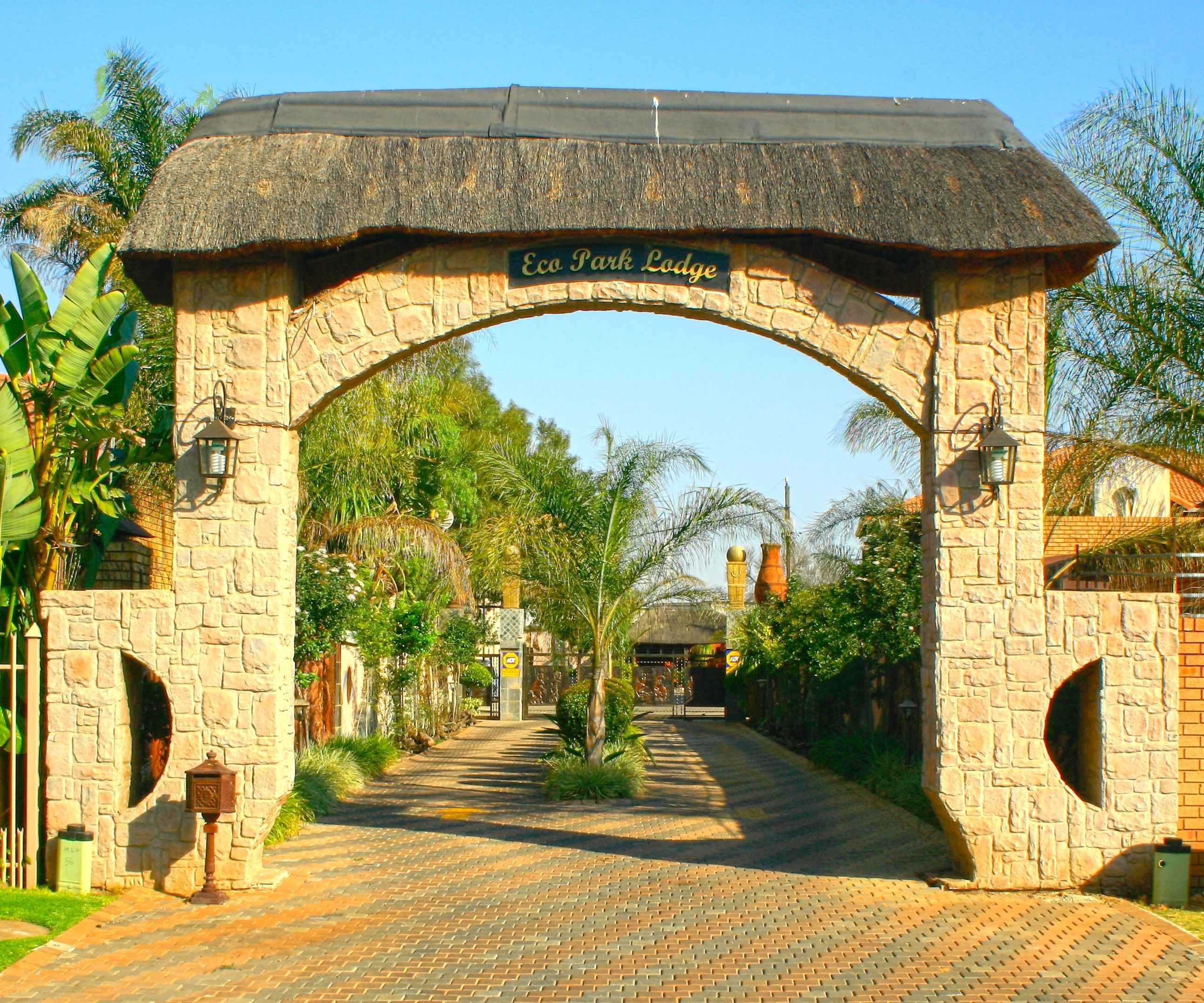 Un arco de entrada con el letrero "Eco Park Lodge" y un camino pavimentado que lo atraviesa.