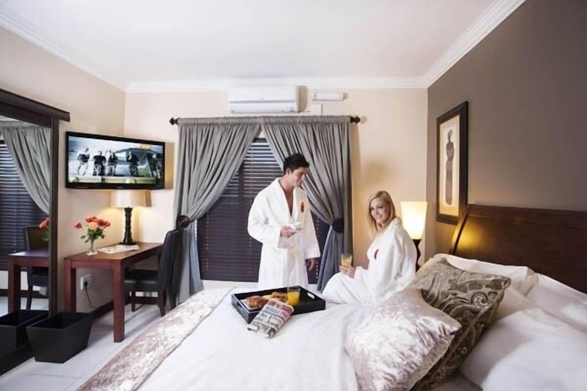 Une chambre d’hôtel avec un lit, un bureau, une télévision et une fenêtre avec des rideaux.