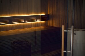 A modern sauna with wooden paneling and a bench. - Plesners Badehotel (Skagen)