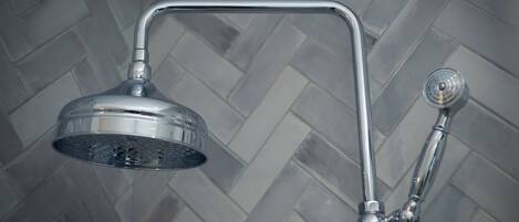 A shower with a curved chrome handle and a round showerhead.
