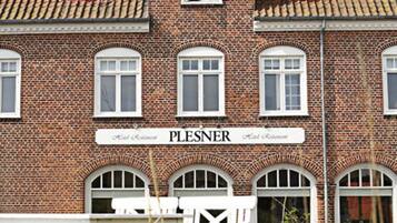 Traditional brick building with a symmetrical facade and arched window, set amidst a charming garden.
