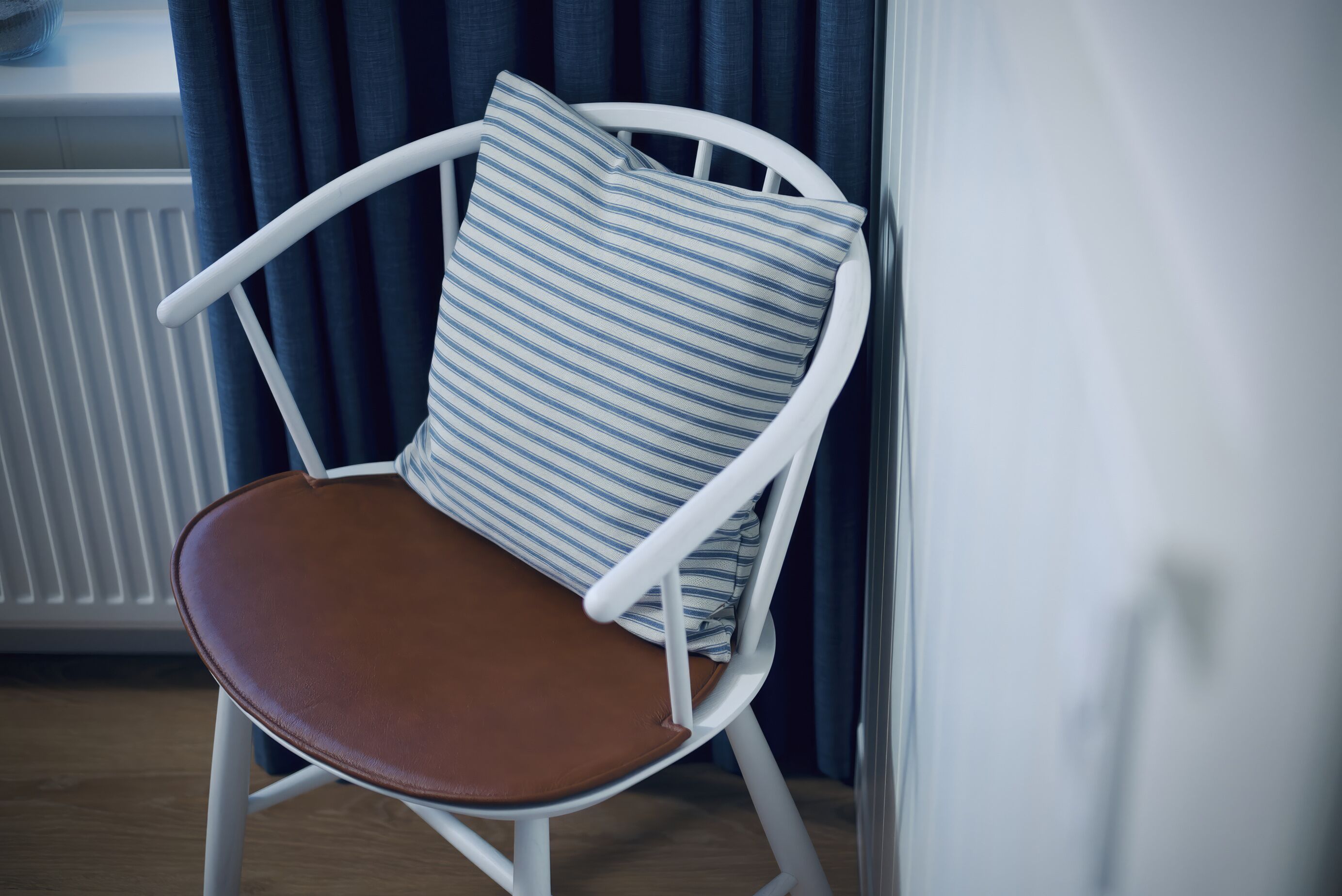 A white chair with a brown seat and a striped pillow.