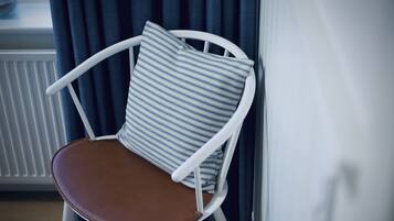 A white chair with a brown seat and a striped pillow.