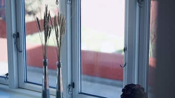 Et vindue med tre vaser med tørrede planter og en enkelt vase med en blomst.