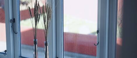 A window with three vases containing dried plants and a single vase with a flower.