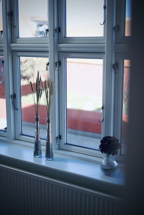 A window with three vases containing dried plants and a single vase with a flower.