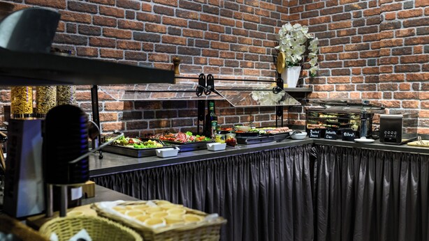 A buffet setup with various food items and a brick wall background. - Hotel Ambassador Essen (Essen)