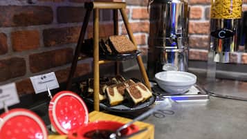 A display of sliced cakes on a stand with a coffee machine and a bowl in the background.