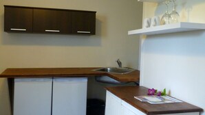Una cocina compacta con encimera de madera, pileta integrada y un refrigerador pequeño.