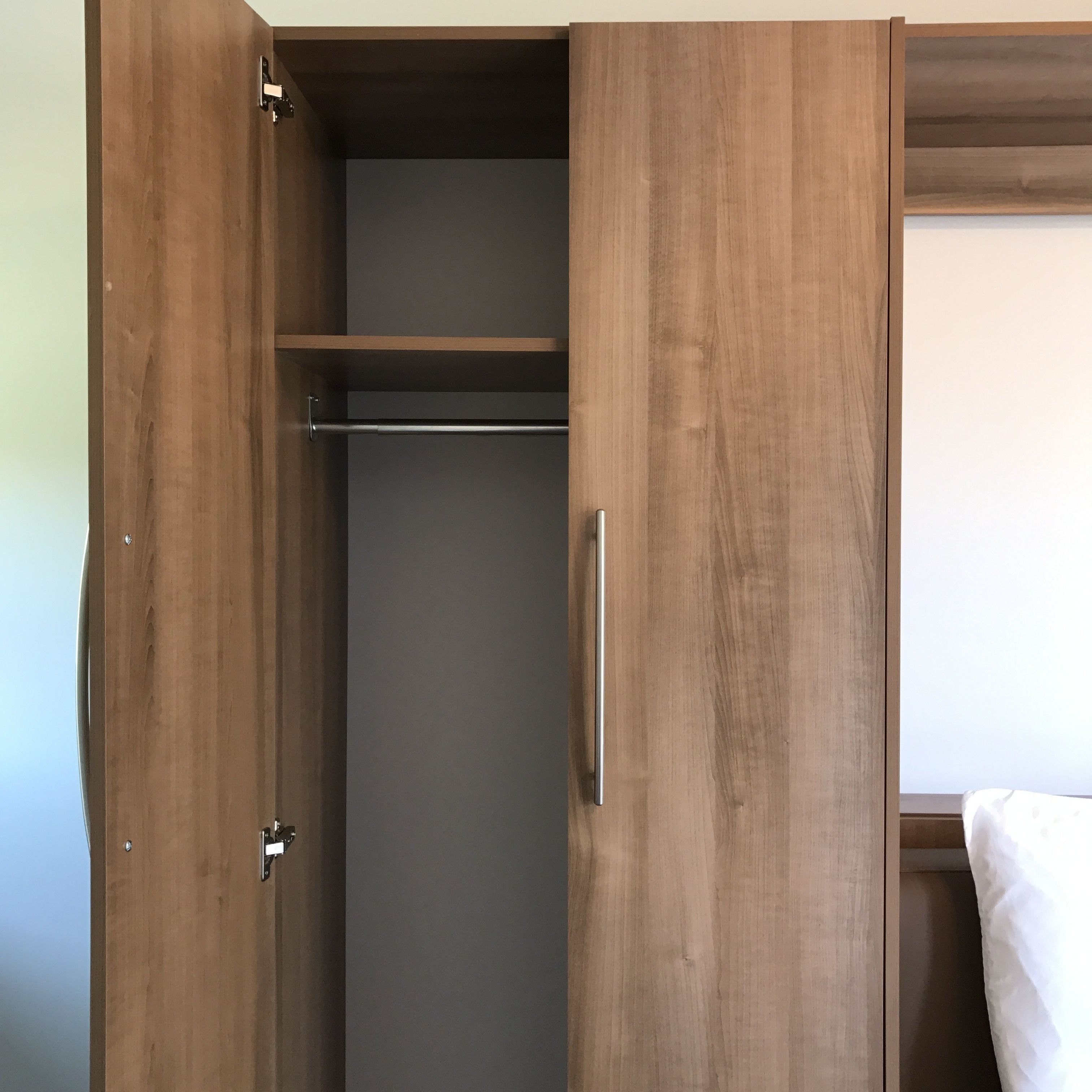 Ein Holzkleiderschrank mit Kleiderstange und Türgriff.